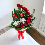 A red roses floral box with white orchids and anthuriums on a white room.