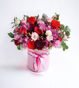 A floral box with red roses burgundy mums and lavender daisies.