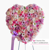 A funeral heart with pink flowers in a standing easel.