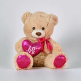 A beige teddy bear with a pink heart on a white backdrop.