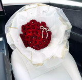 a bouquet of red roses, decorated with pearl bows and white paper wrapping.