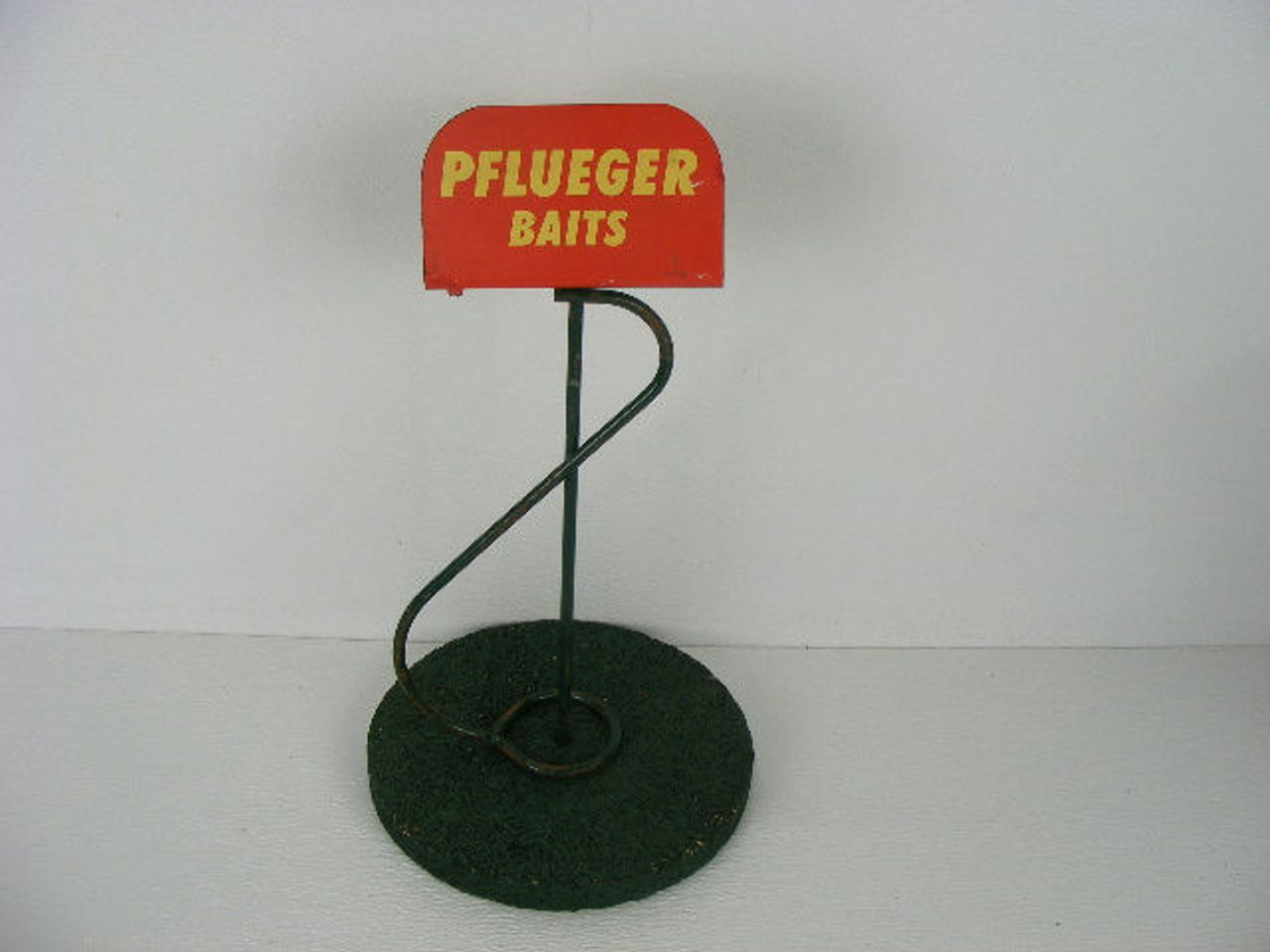 This is an old Pflueger bait fishing lure store display stand with a wood  base and metal sign top.It appears it had some kind of top end cap that  held