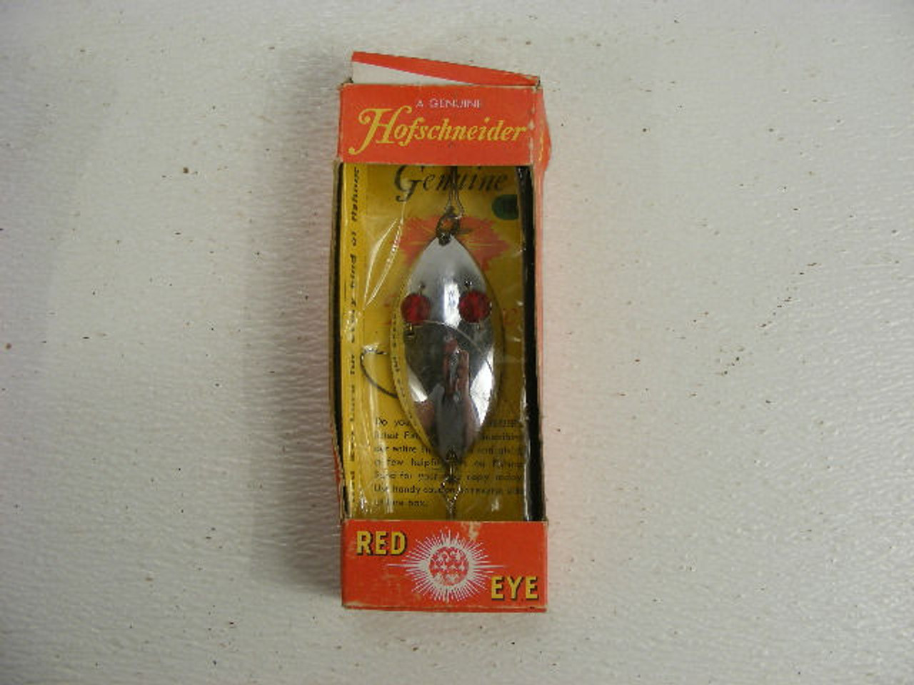 This old lure in the box is a Hofschneider Red Eye that measures 3"  long. - Antique Mystique