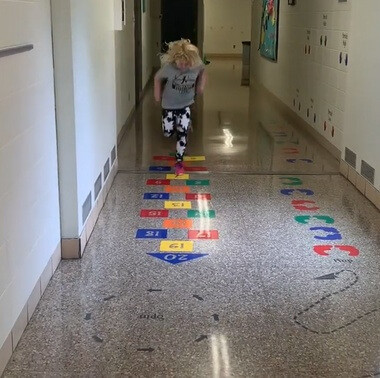 A student running the sensory path hopscotch decals down a school hallway