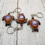 Purple Hibiscus Painted Wooden Sea Turtle Keychain (1 keychain approx. 4.25+ inches) Wooden Sea Turtle Key Fob for gifting or party favors! Copyright 2025 SeaShellSupply.com.