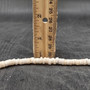 White Puka Shell Necklace - (1 necklace 18 inches x 4-5mm) on grey background. Copyright 2026 SeaShellSupply.com.\n