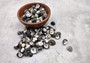 Black Moon Seashells - Nerita Peloronta - (approx. 45-60 shells 0.25-0.75 inches). Multiple black and white spiral shells in a pile. Copyright 2025 SeaShellSupply.com.