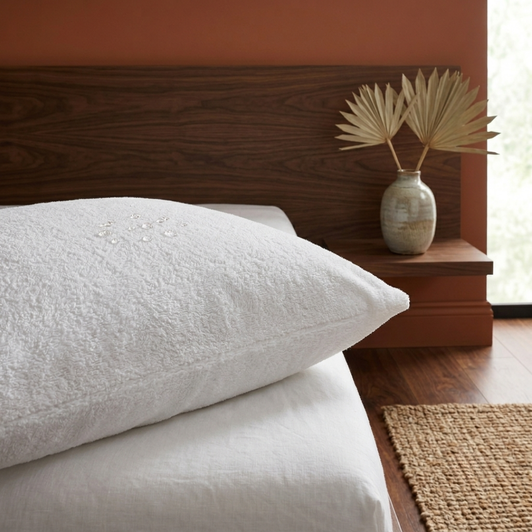 white-terry-towelling-pillow-protector-on-pillow-showing-water-resistant-surface