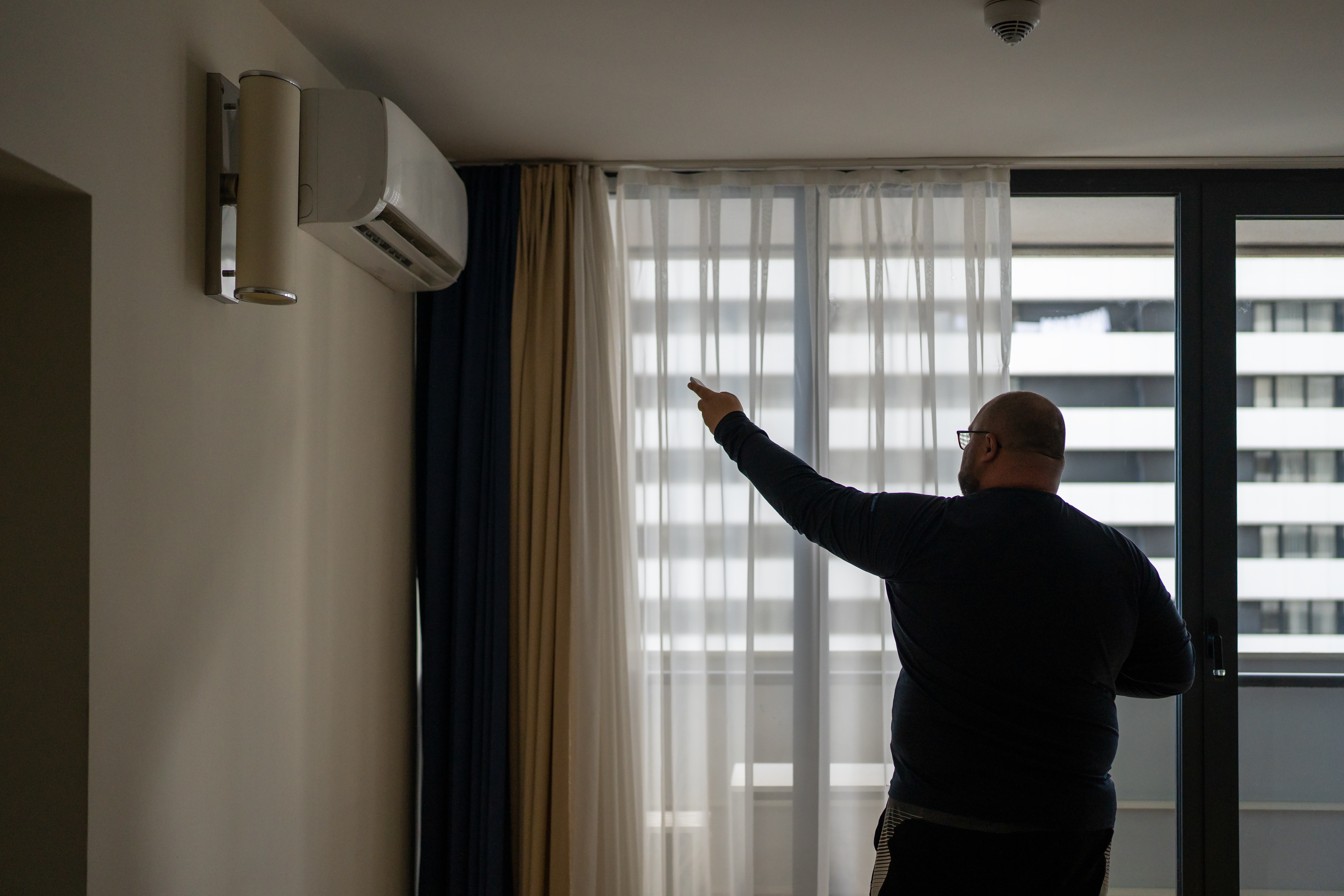 overweight-man-switches-on-air-conditioner-at-home-2023-11-27-05-03-29-utc.jpg