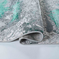 aqua grey abstract rug folded on white floor