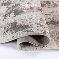 pink grey abstract rug folded on a white floor