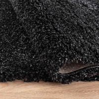 plain shaggy anthracite rug folded on wooden floor