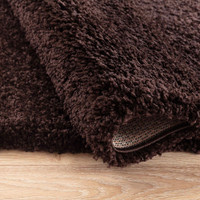 plain shaggy brown rug folded on wooden floor