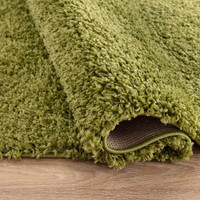 plain shaggy green circle rug folded on wooden floor