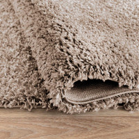 plain shaggy light beige rug runner folded on wooden floor