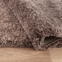 plain shaggy taupe rug runner folded on wooden floor