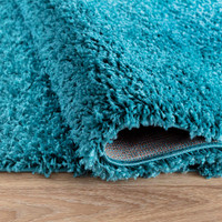 plain shaggy teal rug runner folded on wooden floor