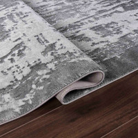 modern abstract abrasion grey rug runner folded on a wooden floor