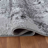 modern abstract sprayed black rug folded on a wooden floor