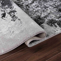 modern abstract sprayed black rug folded on a wooden floor