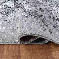 modern abstract sprayed black rug folded on a wooden floor