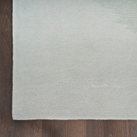 grey seafoam abstract rug closeup corner on a dark wood floor