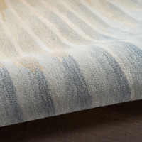 sand abstract rug partially rolled on a dark wood floor