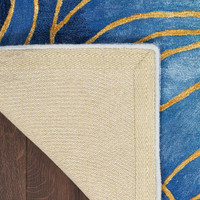 blue gold abstract rug closeup corner folded on dark wood floor