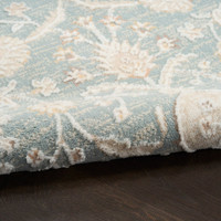 blue traditional rug closeup rolled with dark wood floor