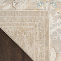 light grey traditional rug closeup corner fold with dark wood floor