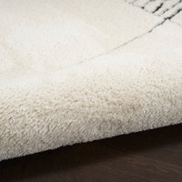 ivory black abstract linear rug partially rolled on a dark wood floor