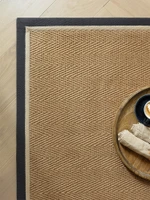 herringbone slate cream jute rug closeup corner with plate on wood floor