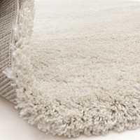 ivory shaggy rug partially folded on white floor