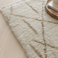 cream berber shaggy wool rug closeup on wood floor