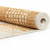 yellow abstract eco rug partially rolled on a white floor