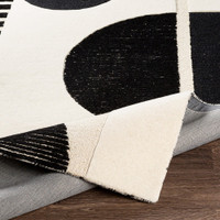 cream geo wool rug corner fold on wood floor