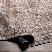 brown traditional rug partially folded on wood floor