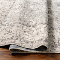 brown traditional rug partially folded on wood floor