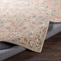 pink traditional rug partially folded on wood floor