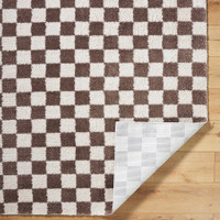 brown checker shaggy rug folded on wood floor