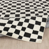 ivory black scandi rug folded on wood floor