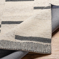 beige striped wool rug folded on wood floor