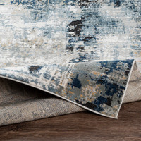 blue abstract rug folded on wood floor