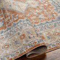 orange traditional rug folded on wood floor