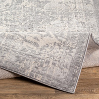 grey traditional rug folded on wood floor