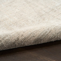 grey abstract rug partially rolled on wood floor