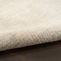 ivory beige abstract rug partially rolled on wood floor