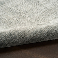slate abstract rug partially rolled on wood floor