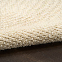 ivory beige rug partially rolled on wood floor