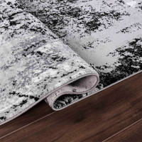 modern abstract acrylic black rug folded on a wooden floor